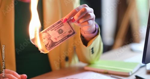 Woman sets fire to ten dollar bill with match. Burning money concept photo