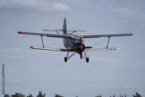 Fototapeta Naklejka Na Ścianę i Meble -  AIRPLANE - A biplane approaches to land at a field airport