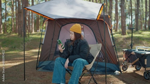 Young asian woman tourist using mobile phone and lost connection signal while camping. Female travel and camping alone confused with phone, problem or poor signal. Network issue. Travel concept photo