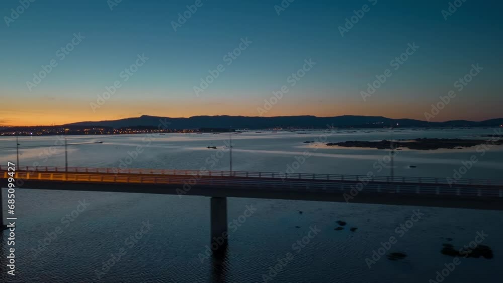 Aerial hyper-lapse view of cars driving on a long sea bridge at sunset with a beautiful golden color reflection on the surface of the sea. Concept of transportation and travel in Europe Aerial hyper-lapse view of cars driving on a long sea bridge at sunset with a beautiful golden color reflection on the surface of the sea. Concept of transportation and travel in Europe