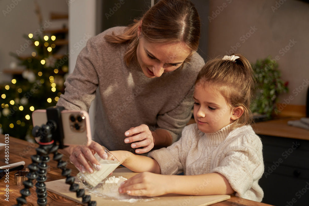Mother and daughter taking recipe for gingerbread cookies from the mobile phone Mother and daughter taking recipe for gingerbread cookies from the mobile phone