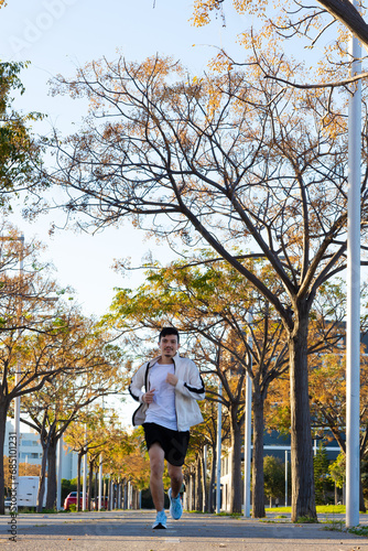 young sportsman running between trees in the city on a sunny day in the morning