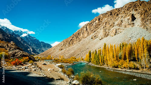 Picturesque landscape with yellow trees, bright blue river and vast surrounding mountains