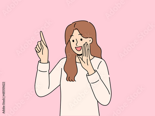 Happy woman tells secret by putting palm to mouth and pointing finger up to recommend paying attention to advertisement. Cheerful girl sharing secret by telling important information or life hacks