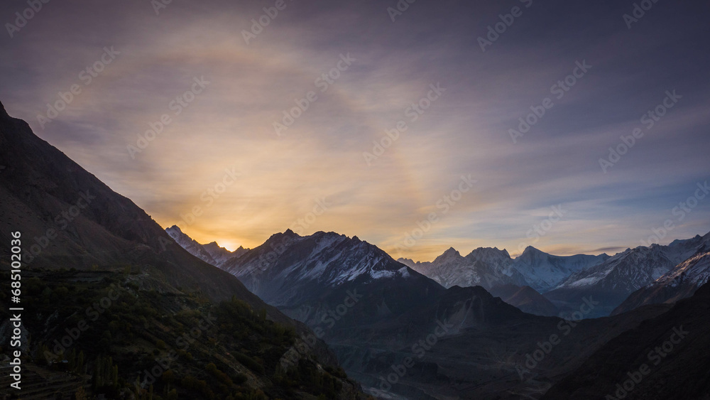 Sunrise with lens flare over vast mountains with snow