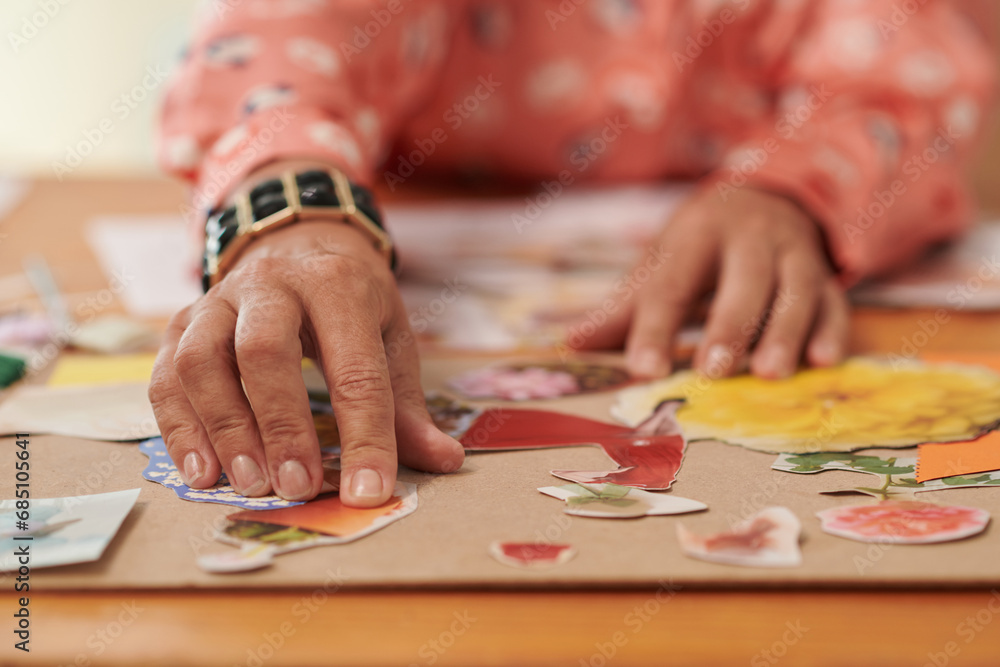 Fototapeta premium Closeup image of creative woman glueing cut photos of flowers on cardboard piece