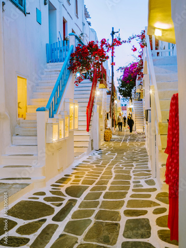 Fototapeta Naklejka Na Ścianę i Meble -  Mykonos Greece in the evening, colorful streets of the old town of Mykonos, Traditional narrow street with blue doors and white walls and street lanterns, shopping street, Mykonos town Greece