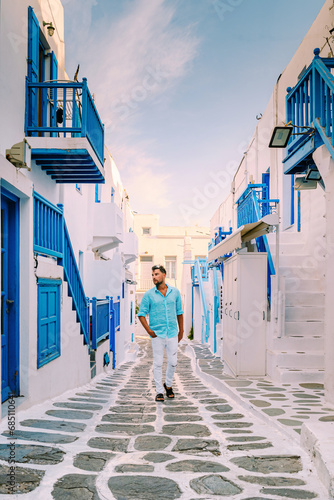 Mykonos Greece, Young man at the Streets of old town Mikonos during a vacation in Greece, young men on vacation holiday in Europe walking at Little Venice Mykonos Greece.