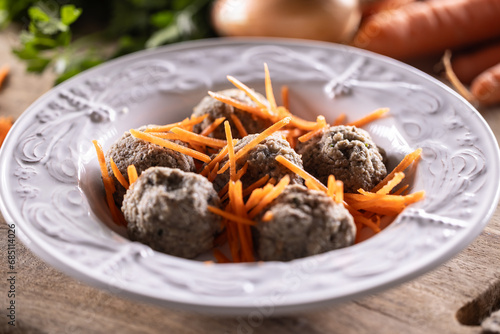 Liver dumplings made of beef liver, bread, eggs and parsley cooked in beef broth placed in a plate with grated carrots photo