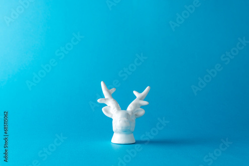 White painted reindeer head on blue background. Minimal art fant