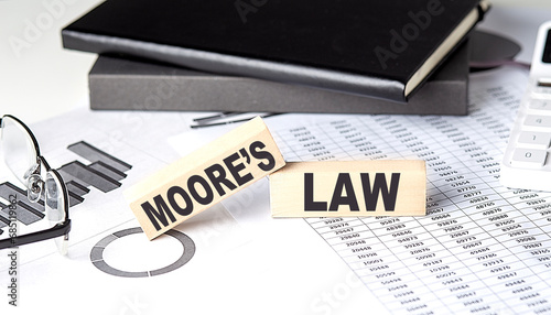 MOORE'S LAW - text on a wooden block with chart and notebook