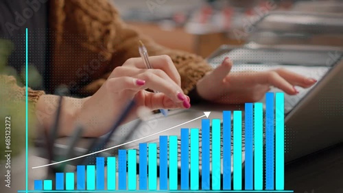 Mujer de negocios trabaja en su laptop tipeando velozmente con sus manos. Analiza las ventas y ganancias de su empres. Un gráfico de barras muestra las ganancias crecientes. photo