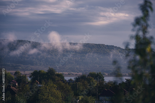 Low rain clouds in misty forest. The lifting of the fog at dawn. The water cycle in nature