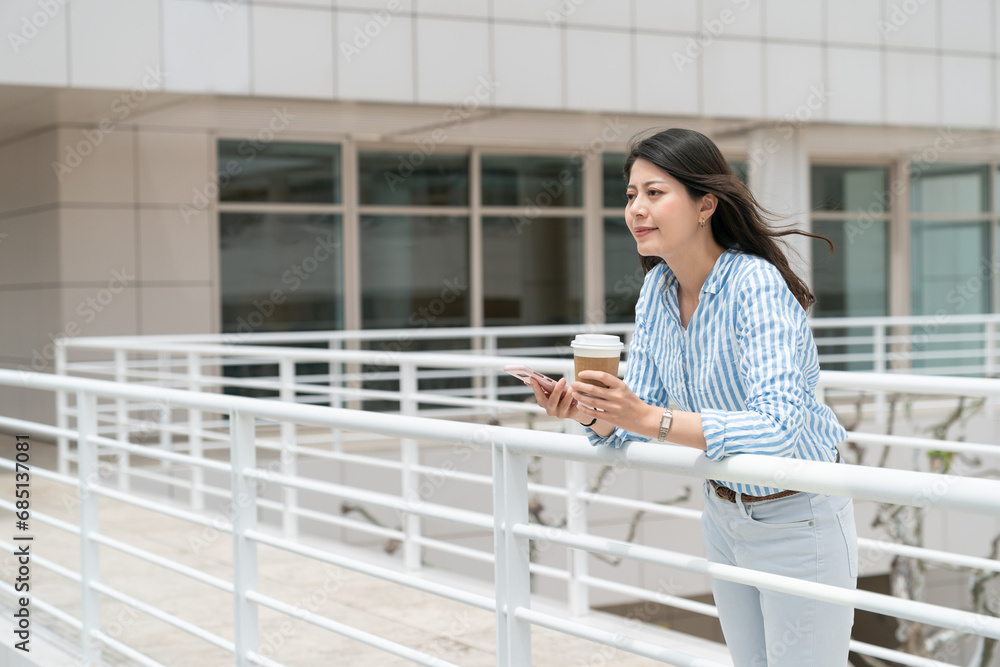 portrait of beautiful asian korean business lady leaning on bridge guardrail and looking into distance with smile and coffee on city background portrait of beautiful asian korean business lady leaning on bridge guardrail and looking into distance with smile and coffee on city background
