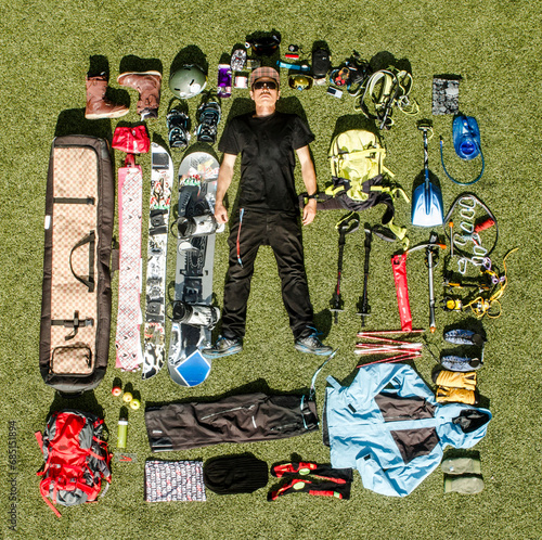 Top view of serious man in black clothes and sunglasses with various hiking equipment lying on meadow photo