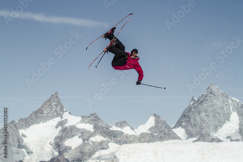Anonymous carefree man skiing and jumping on snowy mountain while enjoying winter day at Swiss Alps photo