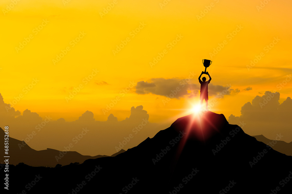 Silhouette businessman standing on top of mountain and holding a trophy with over sunlight for leadership business winner successful and achieve objective target concept.