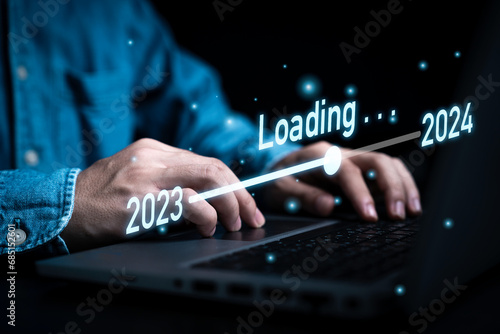 Businessman using laptop computer with downloading tool bar for countdown 2023 to 2024 , Merry Christmas and happy new year preparation by technology concept.