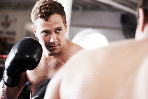 Fight, man and boxer in ring with confidence for fitness, power strike or workout training challenge. Strong hit, boxing and athlete in gym with personal trainer, action and fearless in competition.
