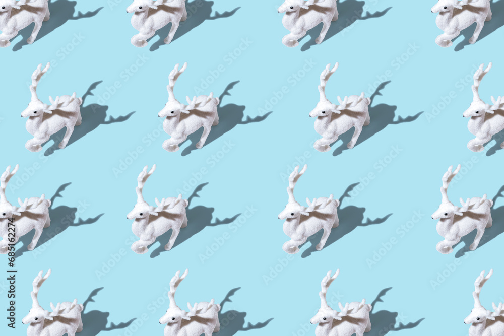 Fototapeta premium Creative Christmas pattern made of Christmas reindeer on bright blue background. Minimal Christmas or New Year concept.