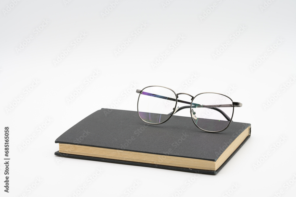 Reading glasses on black book isolated on white background Reading glasses on black book isolated on white background