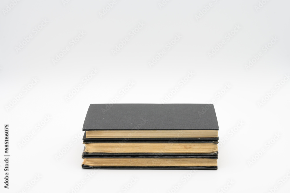 three old books with black covers isolated on top of each other on a white background three old books with black covers isolated on top of each other on a white background