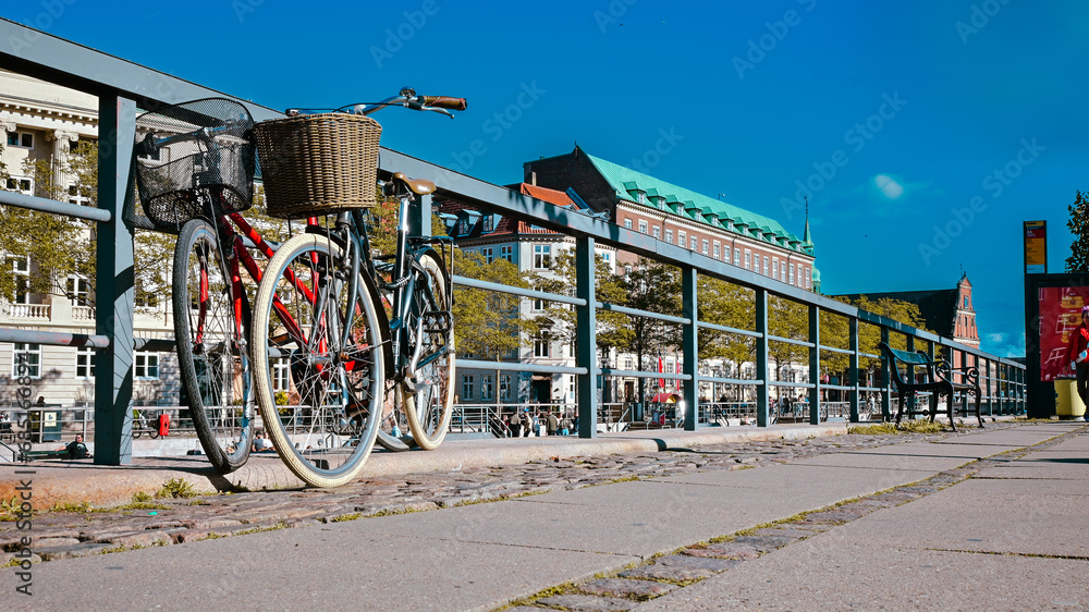 Czerwony i czarny rower oparte o barierkę w starej części   miasta Kopenhaga w Danii. - obrazy, fototapety, plakaty 