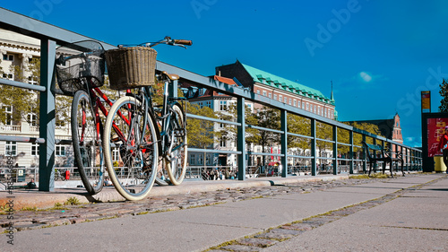 Czerwony i czarny rower oparte o barierkę w starej części miasta Kopenhaga w Danii.