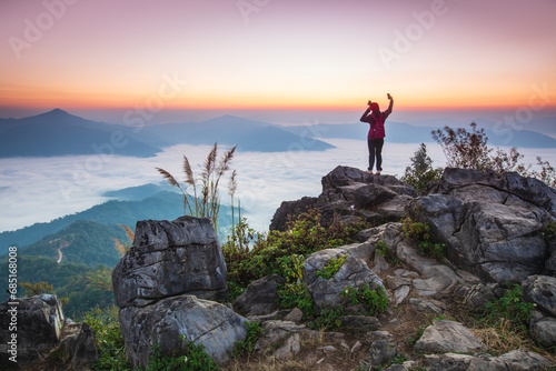 Young woman  in red jacket hiking on the high mountain, Doi Pha Tang, Chiang Rai province, border  of  Thailand and Laos. © Nakornthai