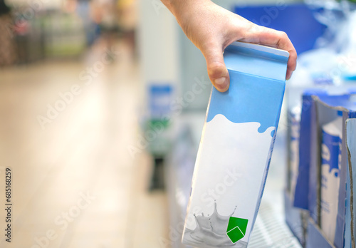 Hand taking a milk carton from supermarket shelf ready for consumption