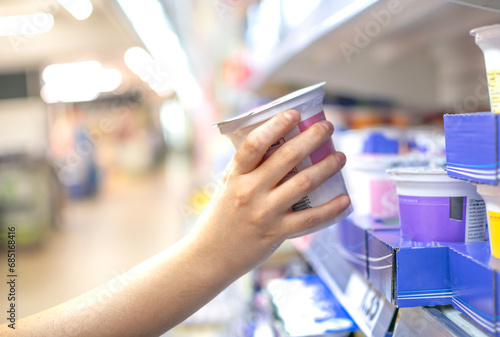 Hand taking Yogurts stored for sale and consumption in supermarkets