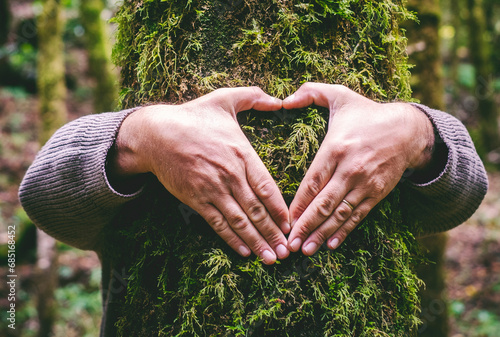One man hugging a green tree trunk doing heart gesture with hands. People and love respect for nature forest and environment lifestyle. Environmentalist embrace trunk with musk. Stop climate change