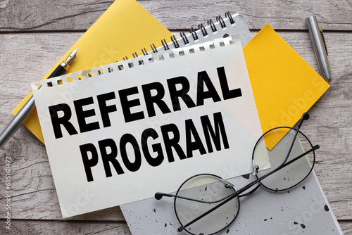 referral program text on paper. gray notepad. glasses, yellow sticker