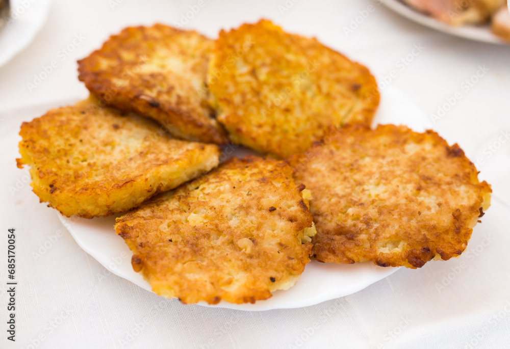 Fried grated potato pancakes with sour cream on white plate Fried grated potato pancakes with sour cream on white plate