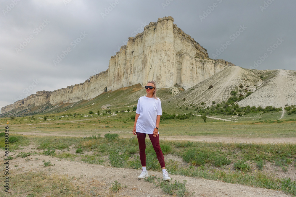 Fototapeta premium A woman on the background of a landscape view of the White Mountain in the Eastern Crimea. Photos of the Crimean peninsula in summer, the white rock of Ak-Kaya, the Biyuk-Karasu river