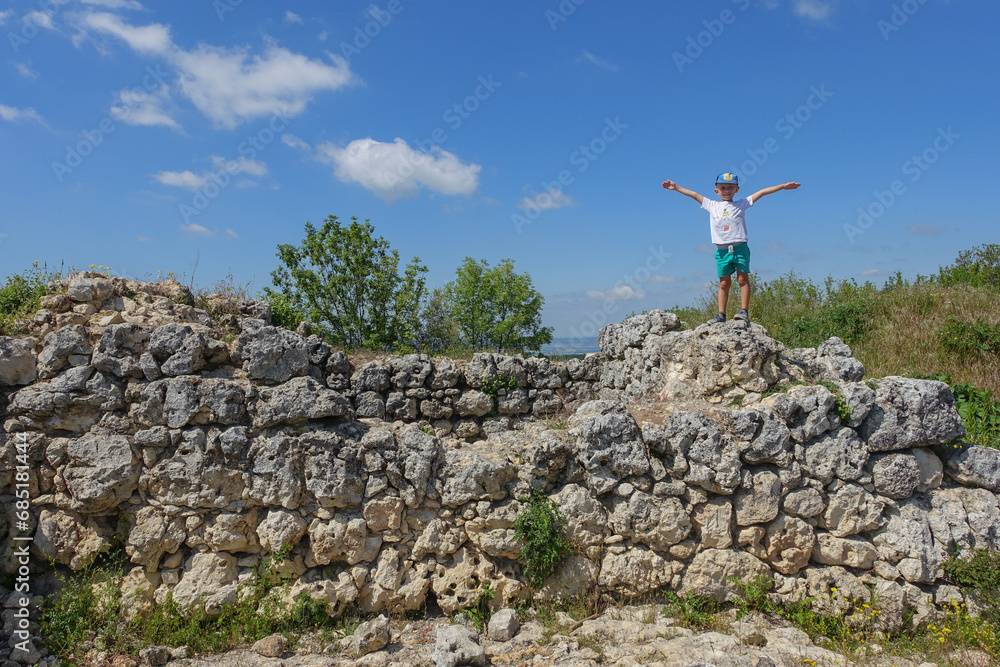 Mangup-Kale cave city, sunny day. A boy on the background of a mountain landscape and buildings of the ancient cave city of Mangup-Kale in the Republic of Crimea, Russia. Bakhchisarai.