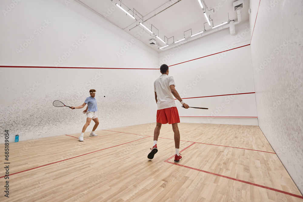 interracial and athletic men in sportswear playing squash together inside of court, motivation