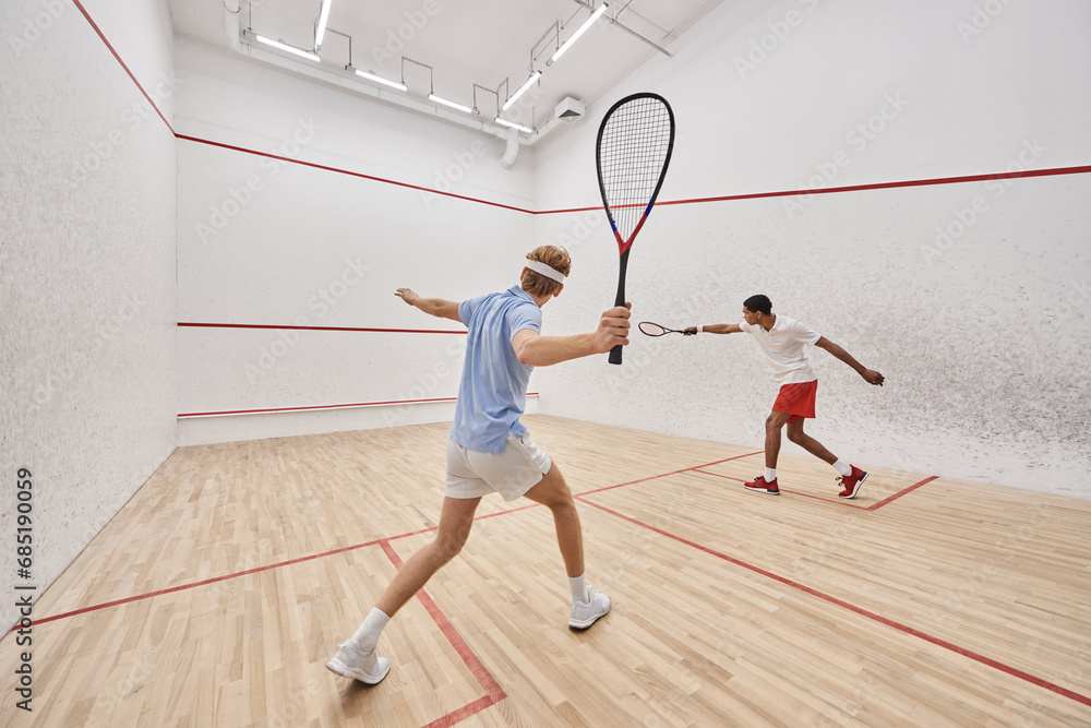 two multicultural players in sportswear playing squash together inside of court, active lifestyle two multicultural players in sportswear playing squash together inside of court, active lifestyle