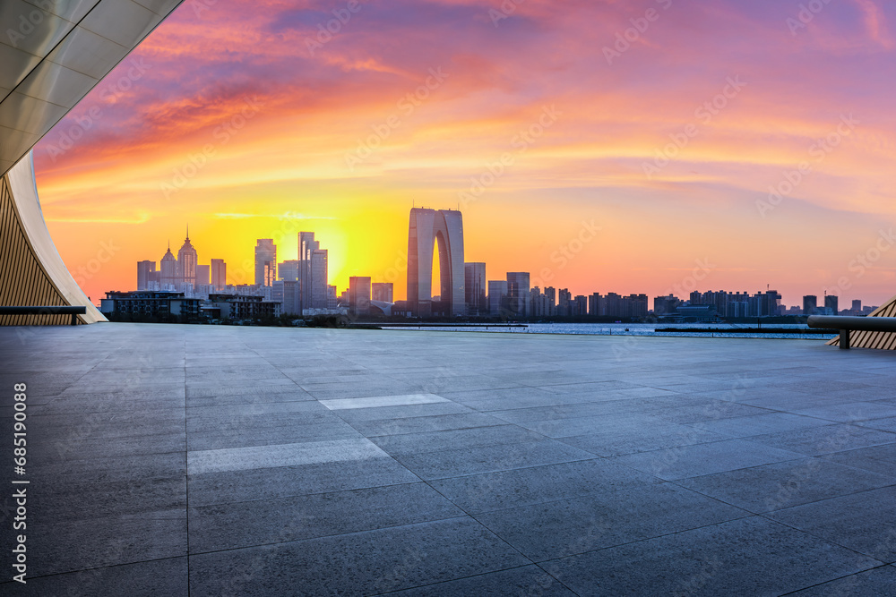 City square and skyline with modern buildings at sunset in Suzhou, Jiangsu Province, China. Empty square floor and city skyline background.