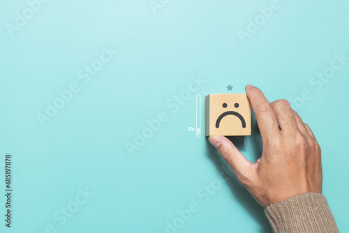 Customer putting wood cube with bad face emoticon for rating. Service rating, feedback, satisfaction concept