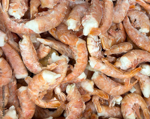 Raw frozen and peeled shrimp background texture. Pile of frozen shrimps pattern. Close-up of frozen shrimps. A lot of royal shrimp macro shot