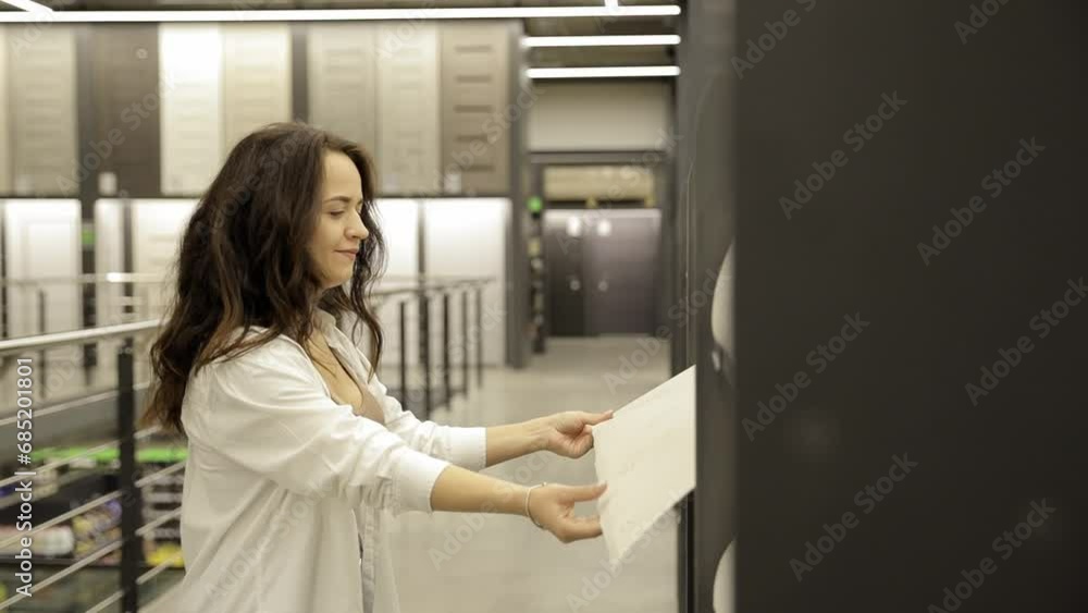 Girl is walking around the construction shop and choosing wallpaper. Girl is walking around the construction shop and choosing wallpaper.