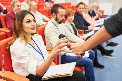 Speaker giving microphone to audience at business session