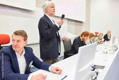 Spekaer with microphone on panel at business conference