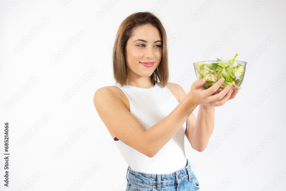 Young woman showing a bowl of salad isolated over white background Young woman showing a bowl of salad isolated over white background