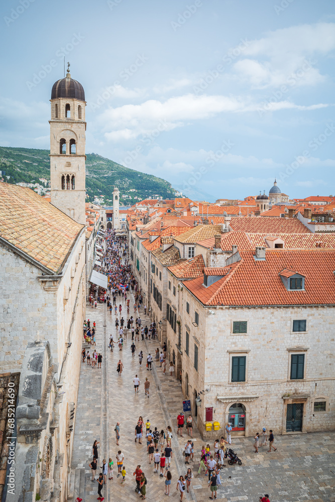View to the red roofs of Dubrovnik Old town on summer day. Crowd of people walking in the streets