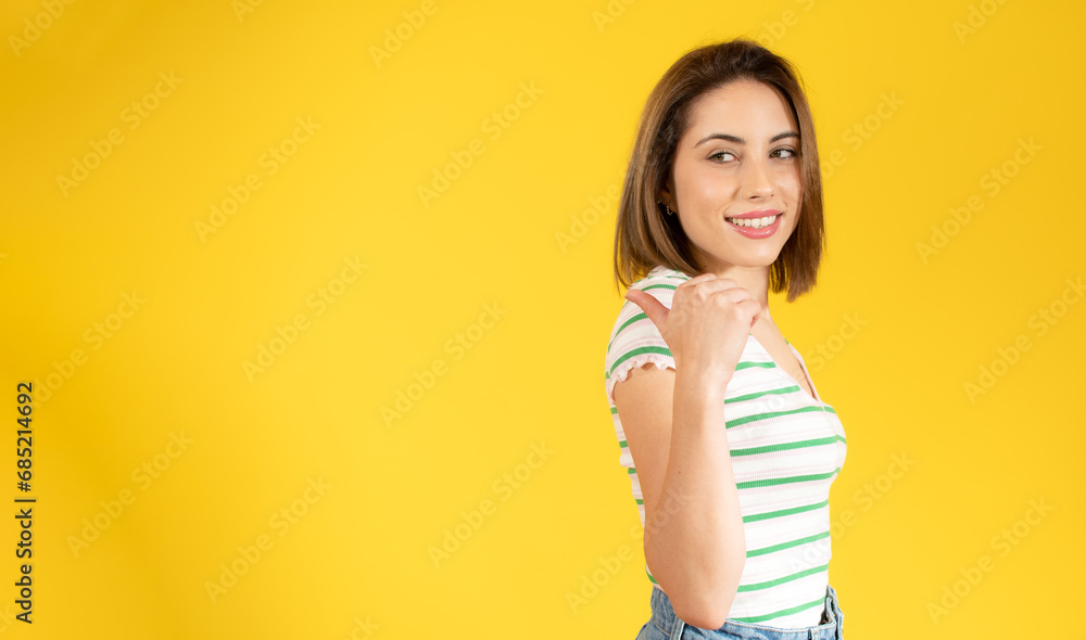 Smiling pretty young woman showing thumb up isolated over yellow background Smiling pretty young woman showing thumb up isolated over yellow background