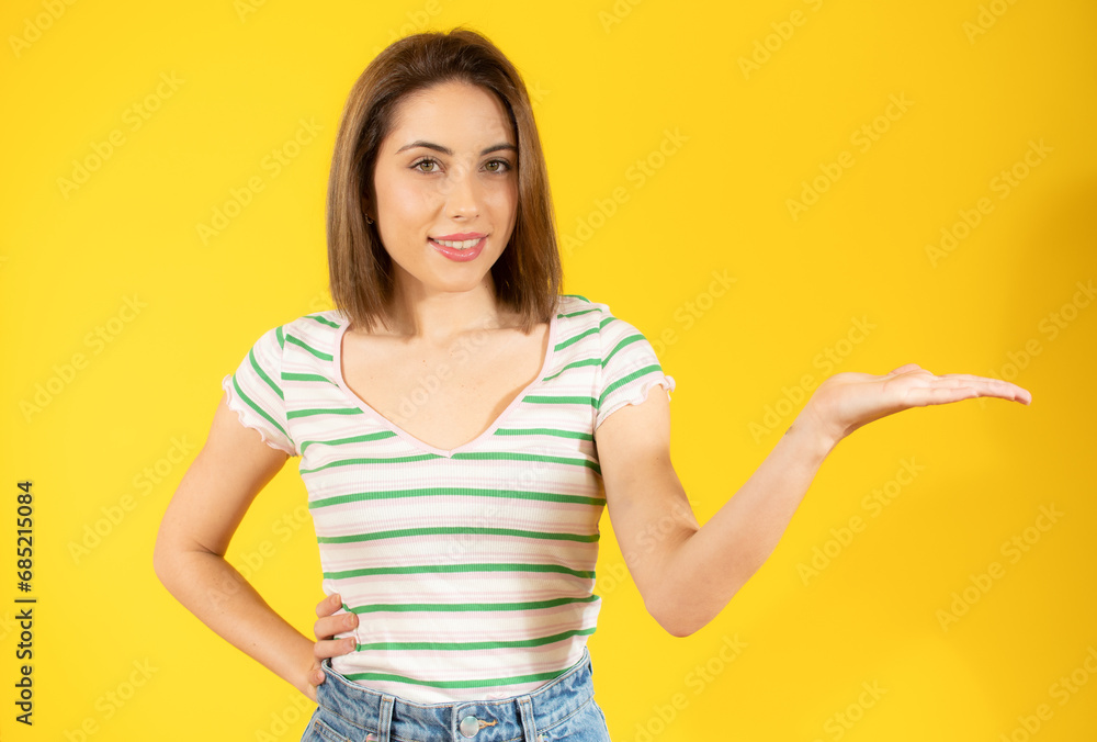Happy woman presenting with open hand holding something blank isolated over yellow background Happy woman presenting with open hand holding something blank isolated over yellow background