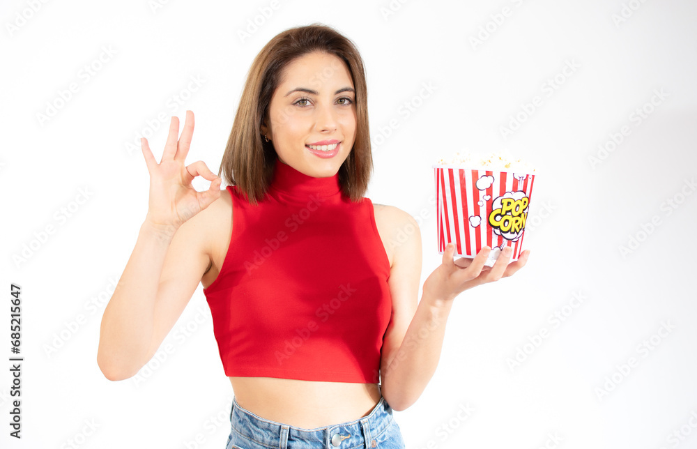 Young beautiful woman eating popcorn with a happy face standing and smiling isolated over white background. Young beautiful woman eating popcorn with a happy face standing and smiling isolated over white background.