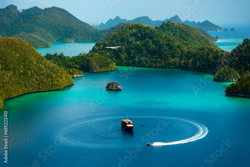 Plane flying over a tourboat and speedboat in a tropical lagoon, Wayag, Raja Ampat, West Papua, Indonesia photo